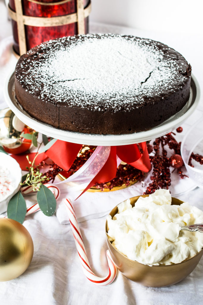 Rich flourless chocolate cake with peppermint whipped cream and crushed candy canes is the perfect Christmas dessert for all of your friends and family.  www.passthecookies.com
