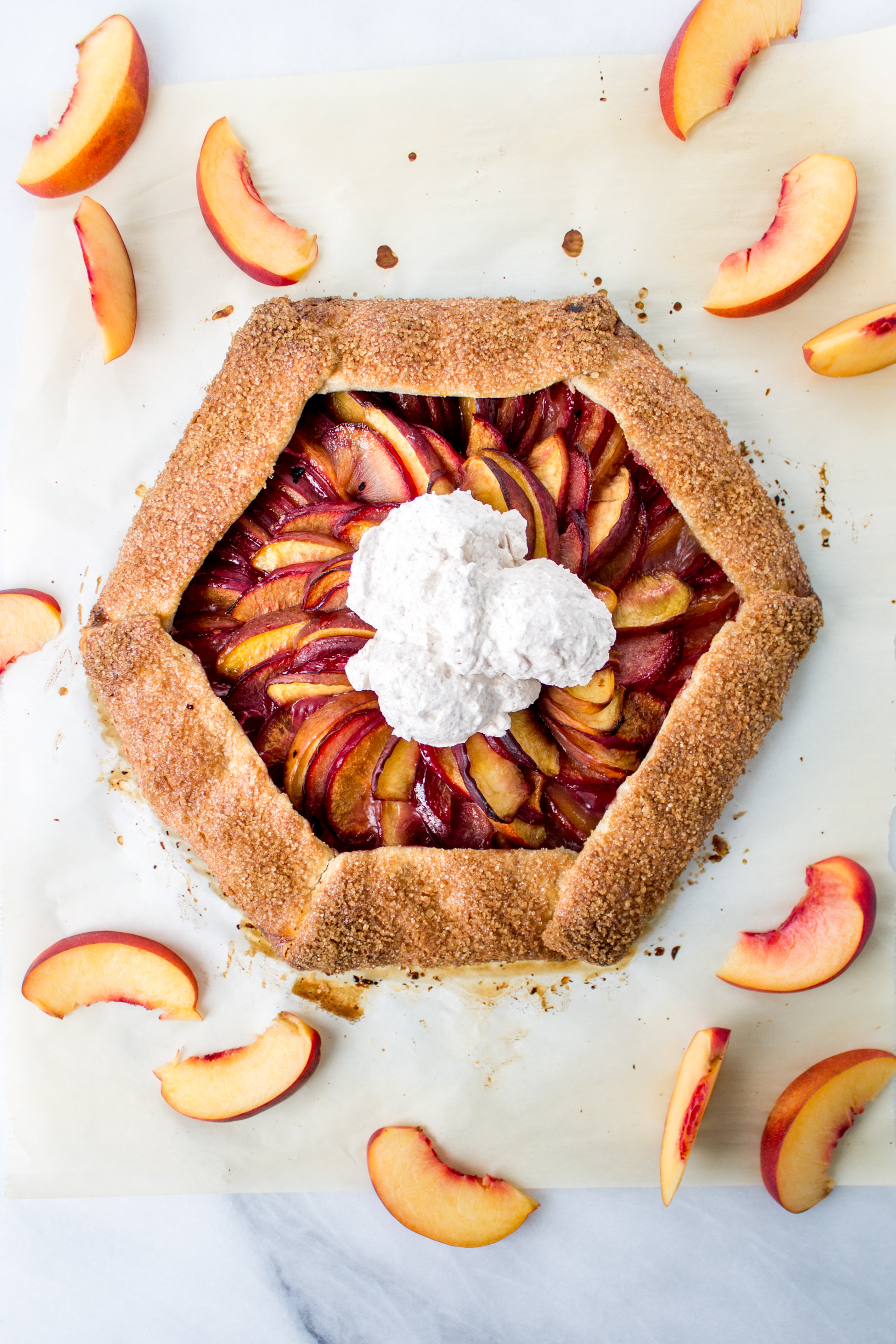 Easier than pie? This plum and peach galette with cinnamon whipped cream is an easy, but impressive and delicious end of summer dessert. | Pass the Cookies | www.passthecookies.com